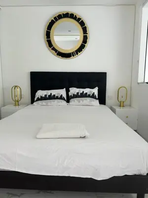 a white bed with a black headboard and a mirror at Normandy in Cannes