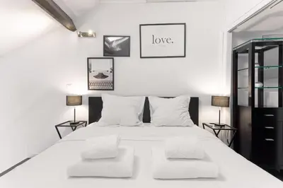 a white bedroom with a white bed with two chairs at Rue Lafontaine by Halldis in Cannes
