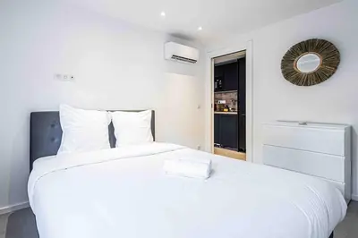 a white bedroom with a large white bed with a mirror at 2 Pcs Plein Coeur Ville, Palace Festivals, Port Plages in Cannes