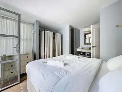a bedroom with a large white bed and a mirror at 126m2 - maison plage, 3 chambres, 3 salles de bain in Cannes