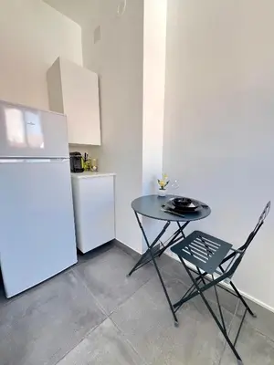 a table and a chair in a kitchen with a refrigerator at studio luxueux in Le Cannet