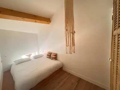 a bedroom with a bed with white sheets and wooden floors at CB Cannes - JUNGLE in Cannes