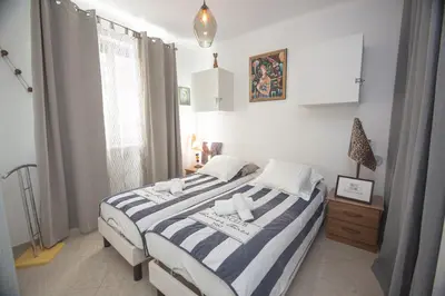 a bedroom with a bed with a blue and white striped blanket at Le Jardin by Connexion in Cannes