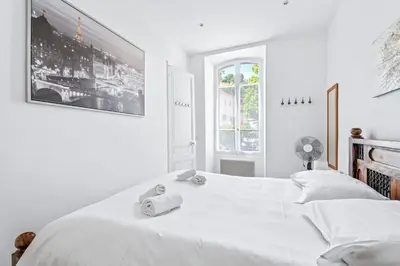 a white bedroom with two beds and a window at Appartement Beau Site - Welkeys in Cannes