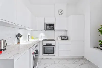a white kitchen with white cabinets and a dishwasher at Appartement Beau Site - Welkeys in Cannes