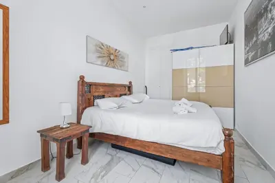 a white bedroom with a bed and a table at Appartement Beau Site - Welkeys in Cannes