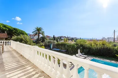 a balcony with a white railing and a swimming pool at Grande villa proche plage vue îles, baie de Cannes in Cannes
