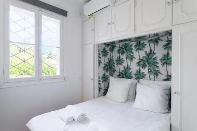 a bedroom with a bed with a tropical wallpaper at Grande villa proche plage vue îles, baie de Cannes in Cannes