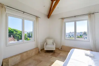 a bedroom with two windows and a bed and a chair at Grande villa proche plage vue îles, baie de Cannes in Cannes