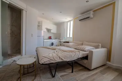 a large bed in a room with a kitchen at Renovated 1 bedroom - AC - City Center in Cannes