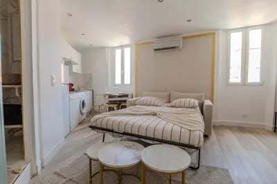 a bedroom with a bed and two tables and a kitchen at Renovated 1 bedroom - AC - City Center in Cannes