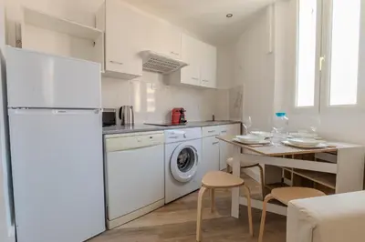 a kitchen with white appliances and a table with chairs at Renovated 1 bedroom - AC - City Center in Cannes