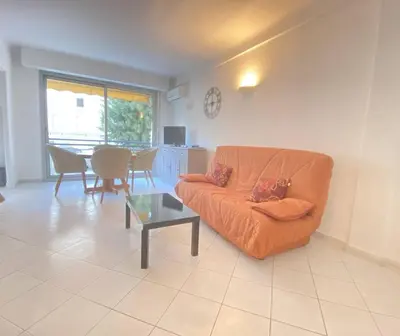 a living room with an orange couch and a table at Cannes proche Croisette - Studio balcon vue sur jardin in Cannes