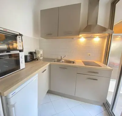 a kitchen with white cabinets and a sink at Cannes proche Croisette - Studio balcon vue sur jardin in Cannes