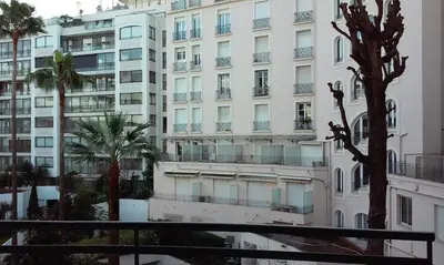 a large white building with palm trees in front of it at Cannes proche Croisette - Studio balcon vue sur jardin in Cannes