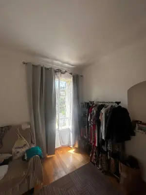 a room with a bed and a window and a clothes rack at La Sérénade in Vallauris