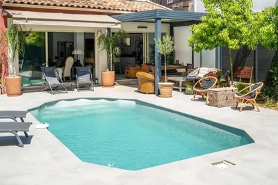 a swimming pool in a yard with chairs and a house at Magnifique villa avec piscine in Le Cannet