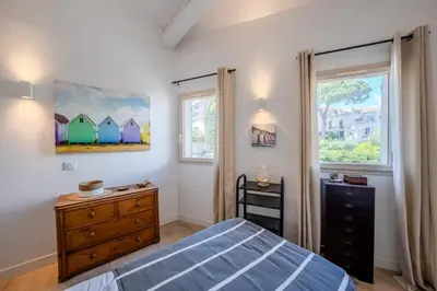 a bedroom with a bed and a dresser and two windows at Magnifique villa avec piscine in Le Cannet