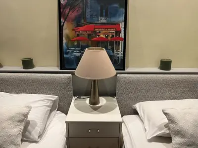 a lamp on a night stand next to two beds at Panter Properies Studio in Cannes