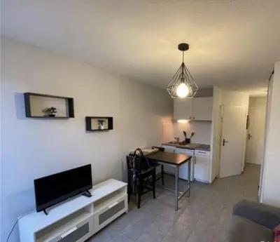 a living room with a dining table and a kitchen at Studio Cannes in Le Cannet
