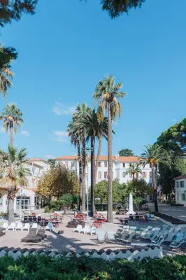 a patio with chairs and palm trees in front of a building at Campus Santa Maria in Cannes