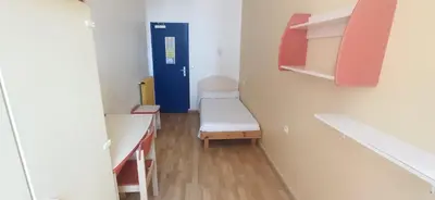 a small room with a bed and a blue door at Campus Santa Maria in Cannes