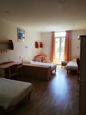 a bedroom with two beds and a table and a window at Campus Santa Maria in Cannes