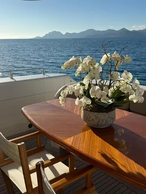 a wooden table with a vase of flowers on a boat at PALME Yacht - Cannes Port Canto - Pointe Croisette - Face à la Mer in Cannes
