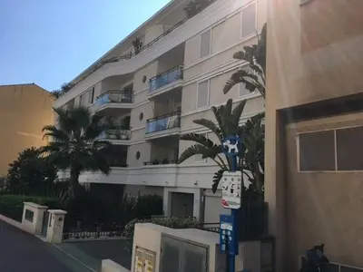 a large building with a palm tree in front of it at Le Carre Montfleury Cannes in Cannes