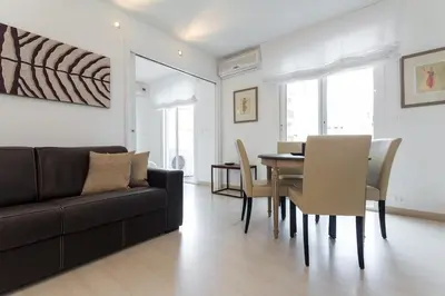 a living room with a black couch and a table and chairs at Charming & Elegant La Croisette apartment in Cannes in Cannes