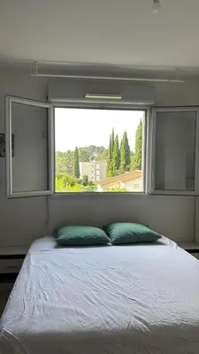 a bed with two pillows in front of a window at T2 42 m2 private residence parking in Le Cannet