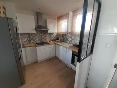 a small kitchen with white cabinets and wooden floors at Appartement rêves d'or in Cannes