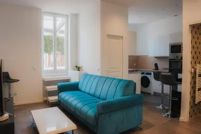 a living room with a blue couch and a kitchen at Cozy Home Cannes in Cannes