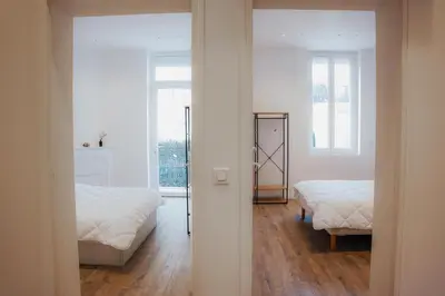a white room with two beds and a window at Cozy Home Cannes in Cannes