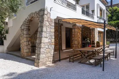 an outdoor patio with a wooden table and benches at REF 2177- Exceptional Villa in the Heart of Cannes 5mins from La Croisette in Cannes
