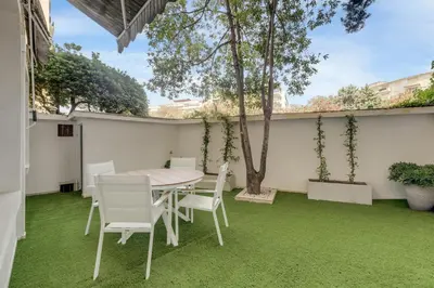 a table and chairs on a patio with green grass at Modern 2 chambres - Jardin - rue du Martinez in Cannes