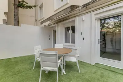 a table and chairs on a patio with grass at Modern 2 chambres - Jardin - rue du Martinez in Cannes