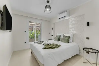 a white bedroom with a large bed and a window at Modern 2 chambres - Jardin - rue du Martinez in Cannes