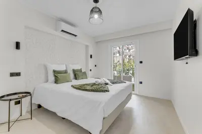 a white bedroom with a large bed and a television at Modern 2 chambres - Jardin - rue du Martinez in Cannes