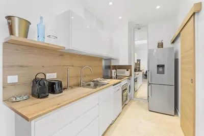 a kitchen with white cabinets and a stainless steel refrigerator at Centre Cannes - 2 Chambres - Proche Palais - Calme in Cannes