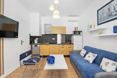 a living room with a blue couch and a kitchen at Centre Cannes - 1 Chambre - Proche Palais - Calme in Cannes