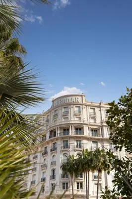 a large white building with palm trees in front of it at Le Miramar Apartment Sea View in Cannes