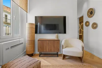 a living room with a tv and a chair at Élégant situé proche du palais in Cannes