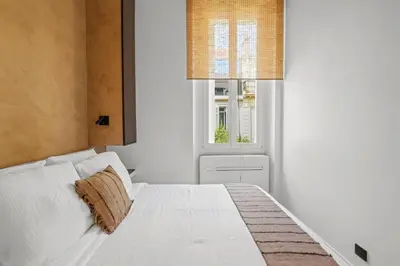a white bed in a room with a window at Élégant situé proche du palais in Cannes