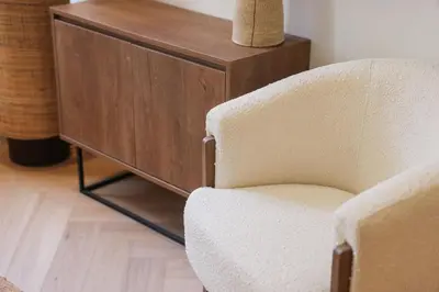 a chair next to a wooden cabinet with a vase at Élégant situé proche du palais in Cannes