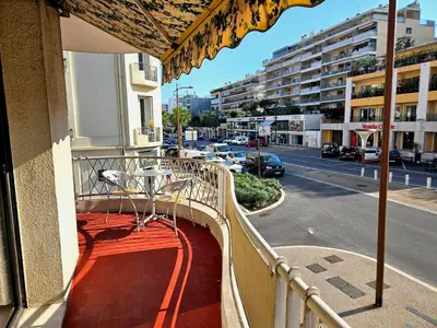 a balcony with a table and an umbrella on a street at Beautiful bright apartment in Cannes