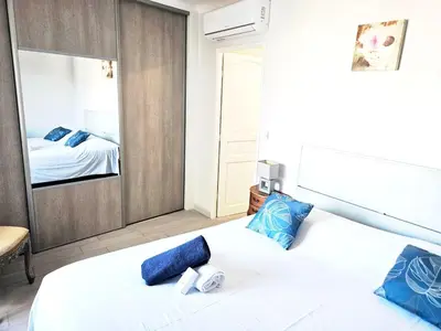 a bedroom with a white bed with blue pillows and a mirror at Beautiful bright apartment in Cannes