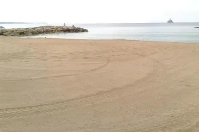 a sandy beach with a group of people in the water at PROMO! Studio, Plein Center, Vieux Port, 200 m des plages in Cannes