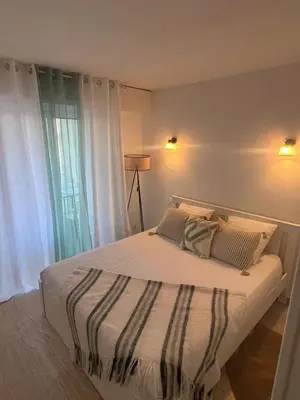 a bedroom with a bed with white sheets and a window at Logements centrale in Cannes
