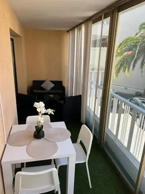 a white table and chairs in a room with a balcony at Logements centrale in Cannes